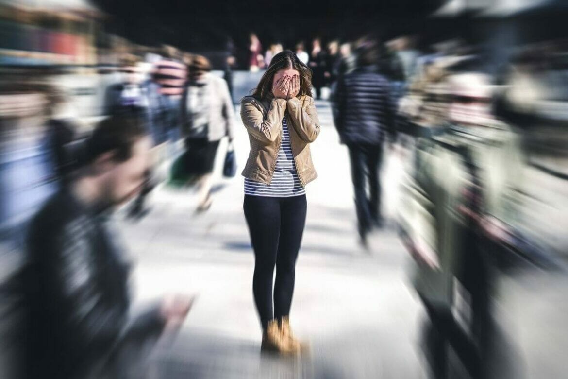 Image of a woman having panic attack due to anxiety amidst a crowd