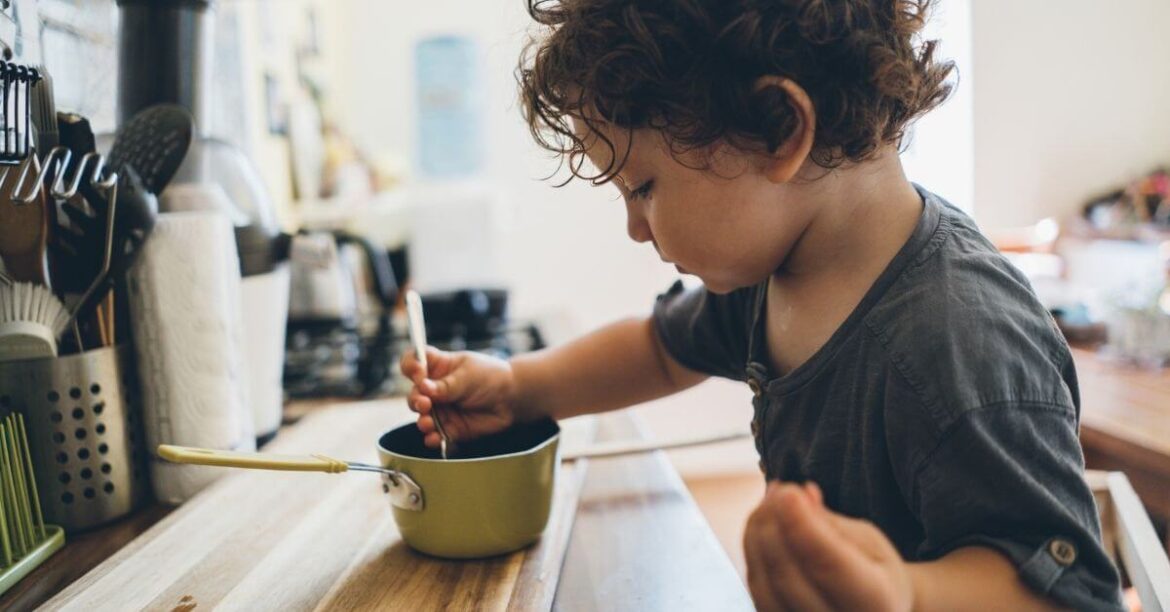 Toddler playing in the kitchen with a bowl and spoon