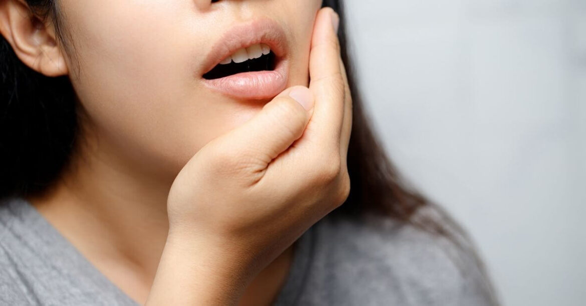 Woman with canker sores aka mouth ulcers pain