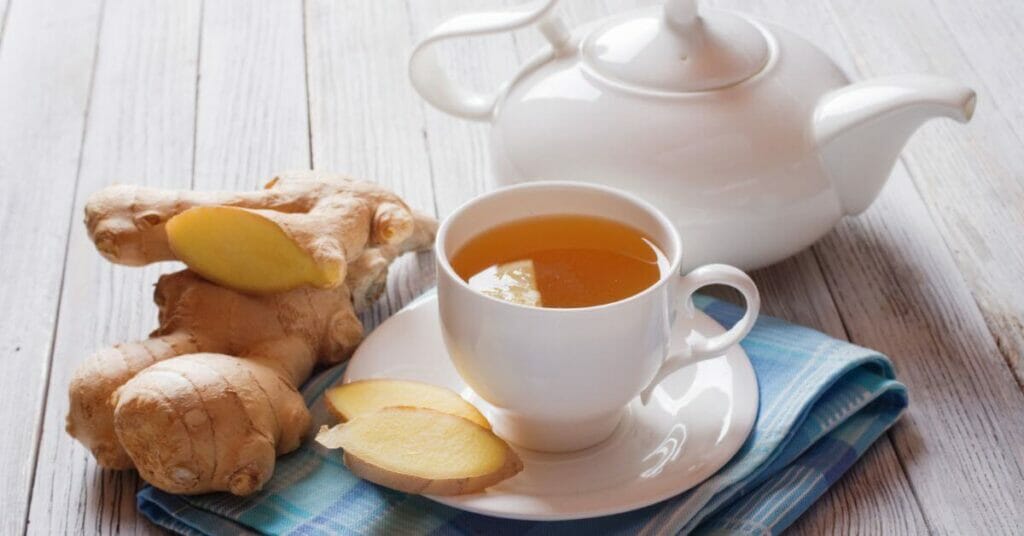 Image of ginger tea in a cup with fresh ginger and teapot