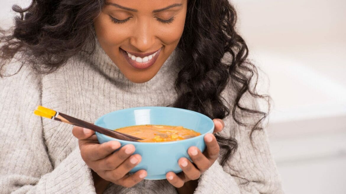 Smiling woman relishing the smell of healthy Moong/Mung dal recipe
