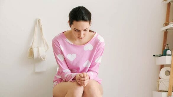 Image of a young woman suffering with constipation; it can be treated with many Indian remedies