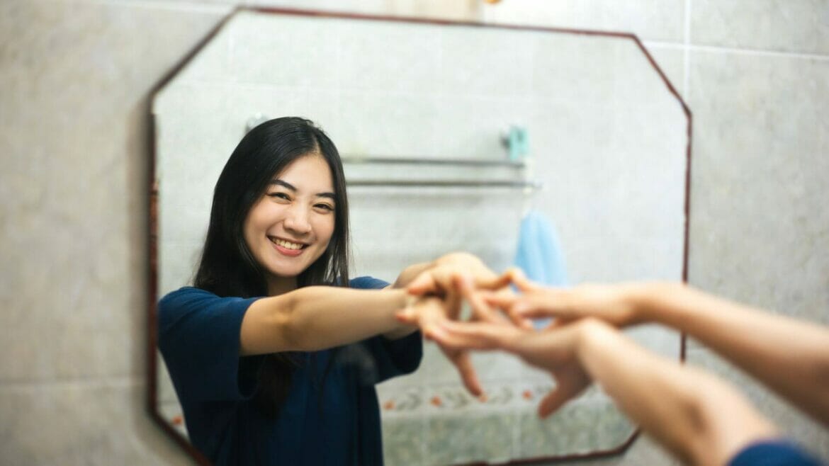 Image of a young woman having positive self-talk before a mirror