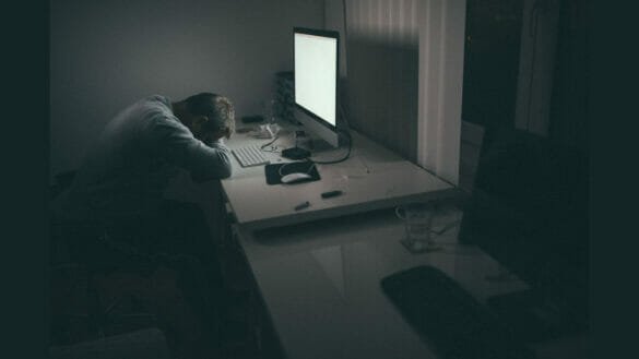 Image of a man taking a daytime nap at his work desk