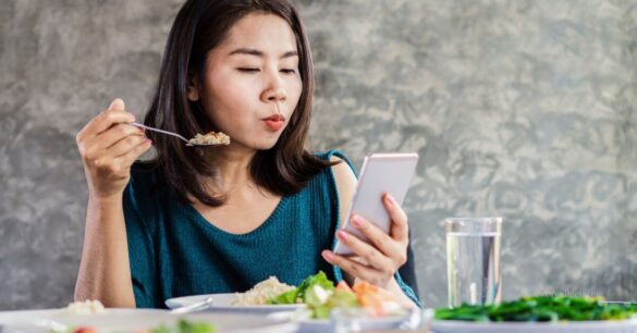 Woman multitasking while eating - mindless eating might lead to weight gain, especially in women 40+